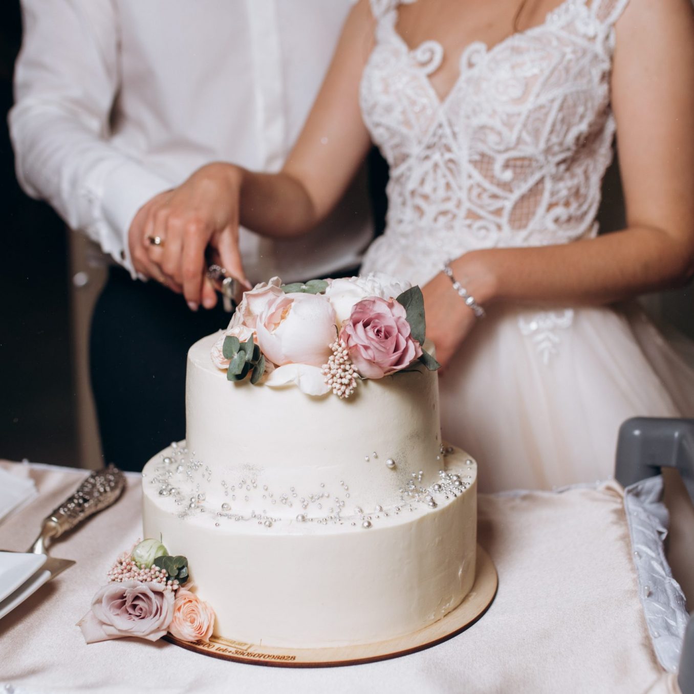 Bride and groom are cutting decorated with flowers wedding cake